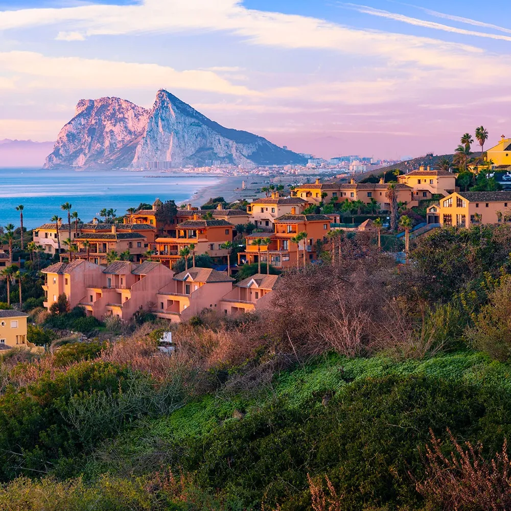 A hillside town on the Andalusian coast with the Rock of Gibraltar behind