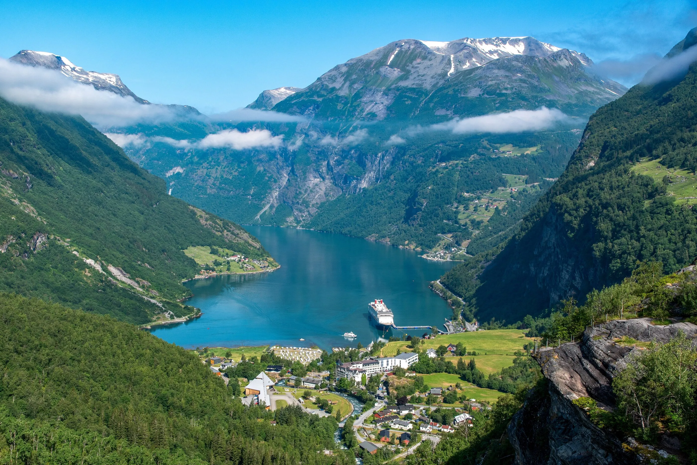 A cruise ship in Geirangerfjord, below snow-capped mountains